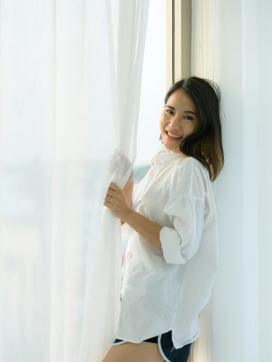 Young woman asian people in the bedroom with white curtains